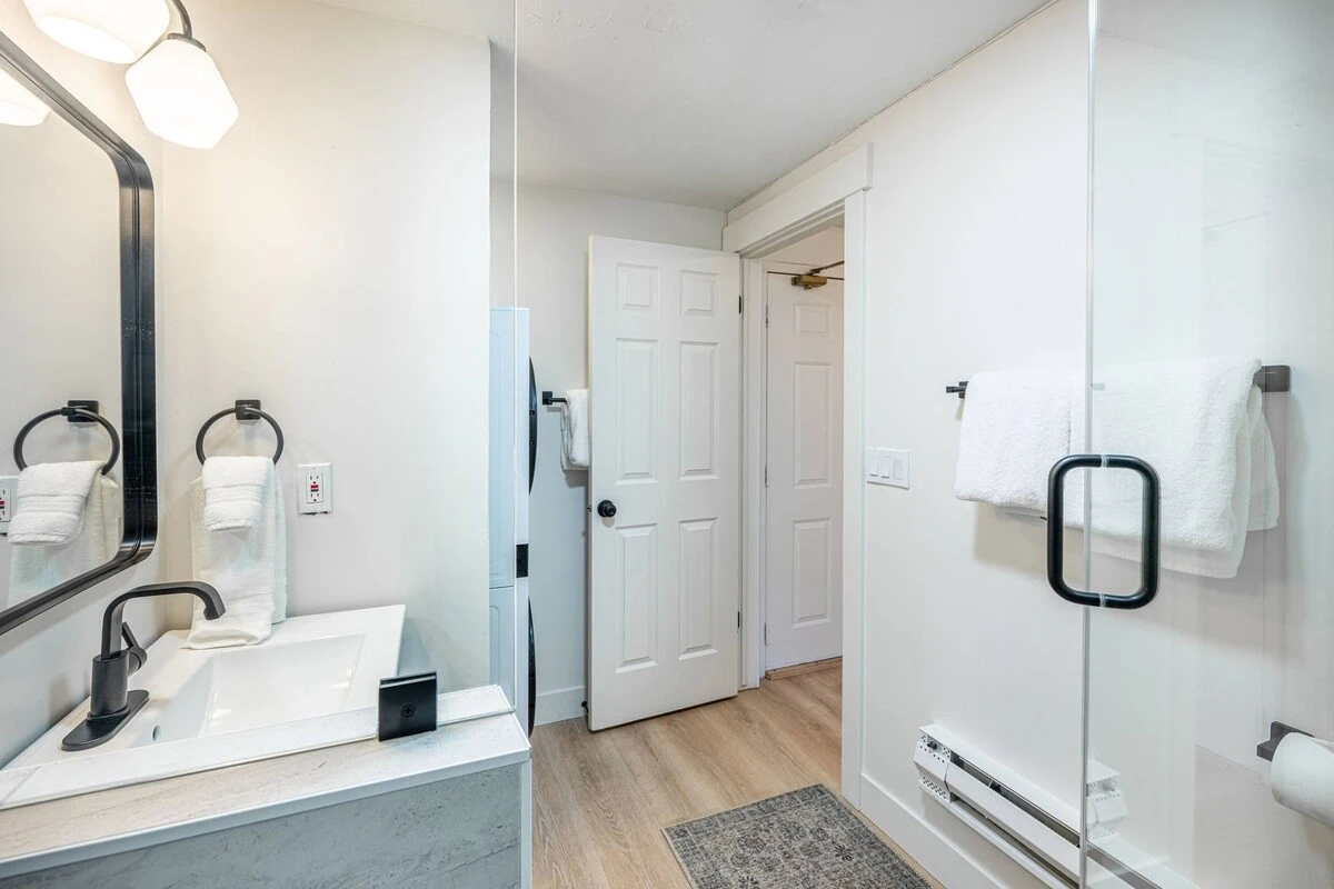Full bathroom with new sage green vanity, walk-in glass shower and toilet