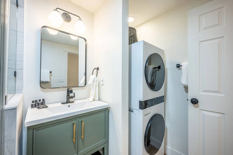 In-home washer and dryer for guest use. Full bathroom with new sage green vanity, walk-in glass shower and toilet. (alternate angle)