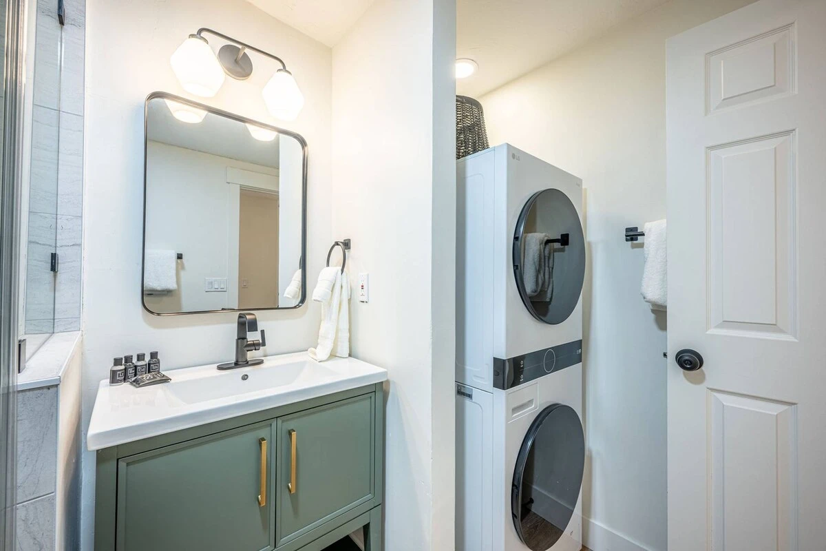 In-home washer and dryer for guest use. Full bathroom with new sage green vanity, walk-in glass shower and toilet. (alternate angle)