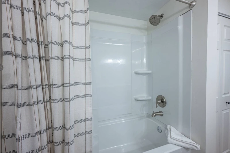 Primary En Suite Bathroom with new shower and bath tub, fresh towels and standard amenities.