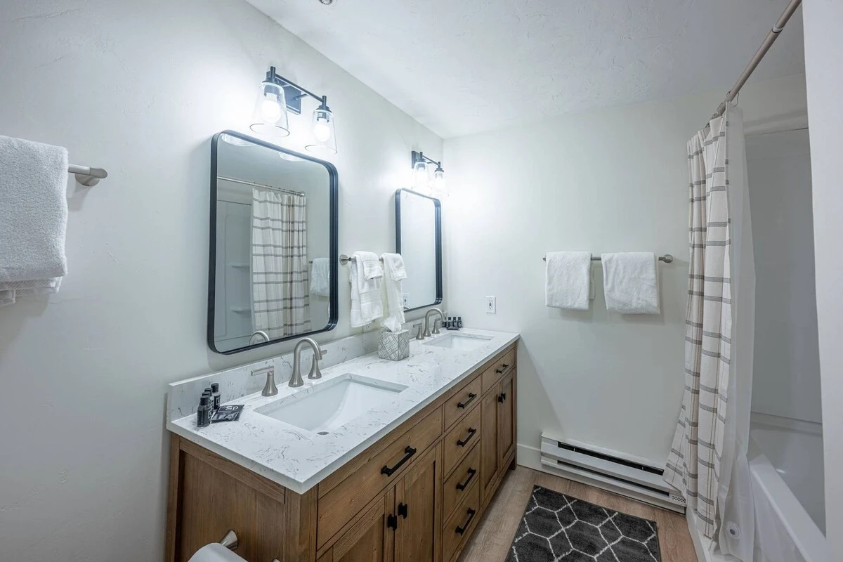 Primary En Suite Bathroom with two sinks, shower/tub, fresh towels and standard amenities.