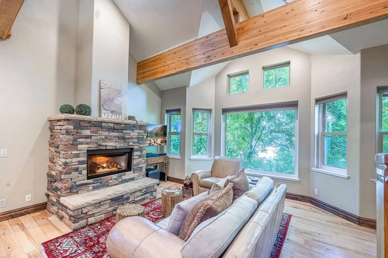 Main living room with vaulted ceilings, large windows, and gas fireplace in this Old Town Park City ski home.