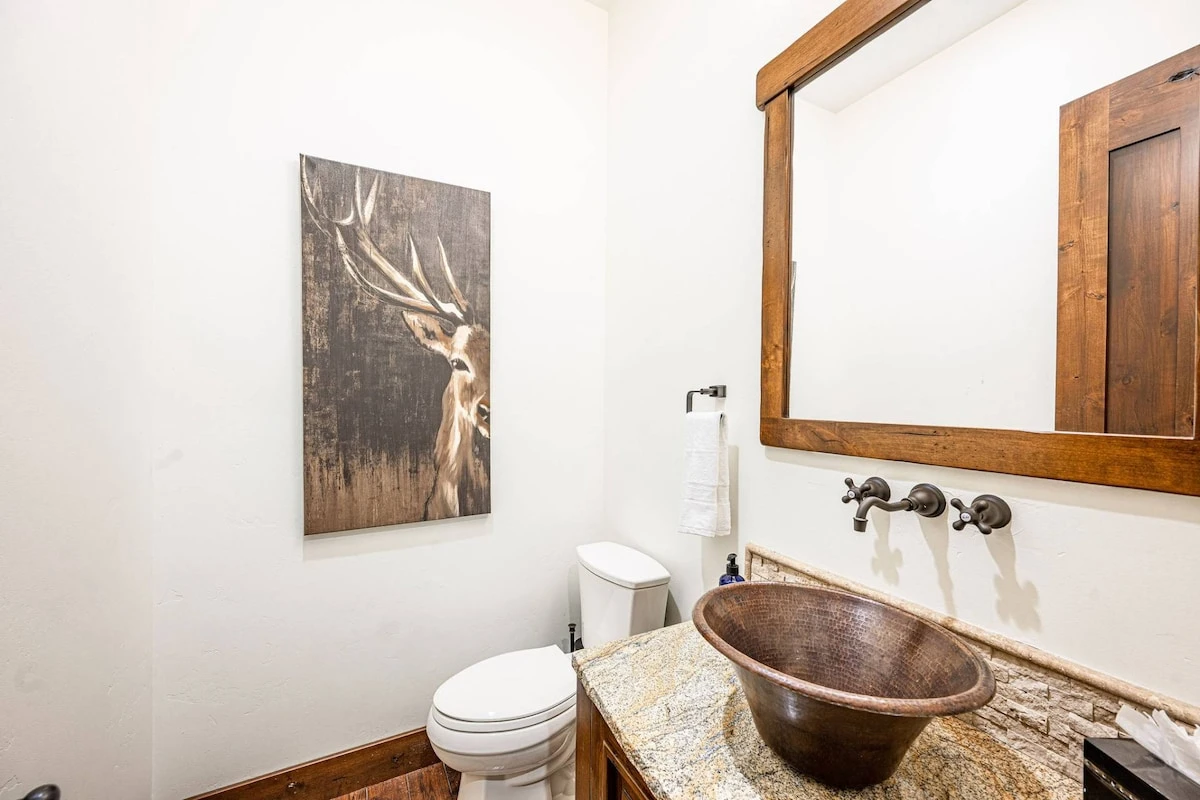 The half bathroom is just off the kitchen and features a unique sink centered on a high end granite countertop
