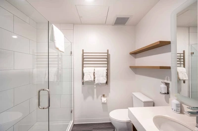 Brand new private and spacious bathroom with a large walk in shower, quartz countertops, and a heated towel rack