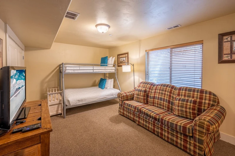 Additional sleeping area downstairs with a triangle bunk bed with a full-sized mattress on the bottom, a twin-sized bed on top and a sleeper sofa