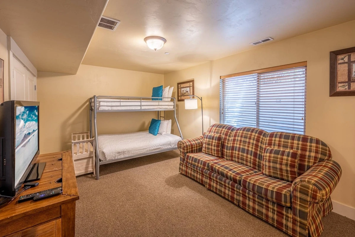 Additional sleeping area downstairs with a triangle bunk bed with a full-sized mattress on the bottom, a twin-sized bed on top and a sleeper sofa