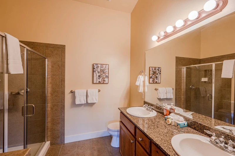 Second bathroom with walk-in glass shower and twin vanities