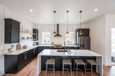 Gourmet kitchen featuring custom lighting, white quartz waterfall edge breakfast bar, high end appliances, everything is here