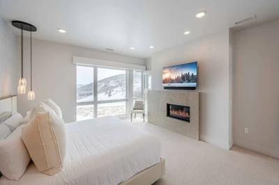 Primary suite with cal-king bed, mountain views, fireplace, and ensuite bath in this luxury Park City penthouse.