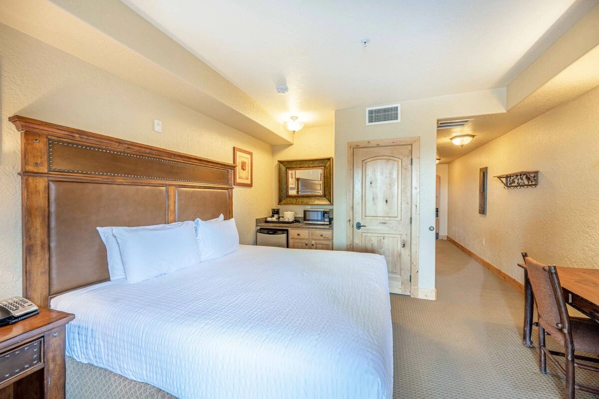 The primary suite features a plush king bed outfitted with professionally laundered, tripled sheeted linens, HDTV, balcony access, comfortable wood de