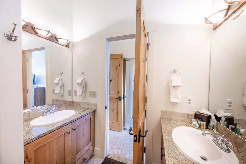 The primary suite en suite bathroom features two separate granite vanities and a walk in glass shower.
