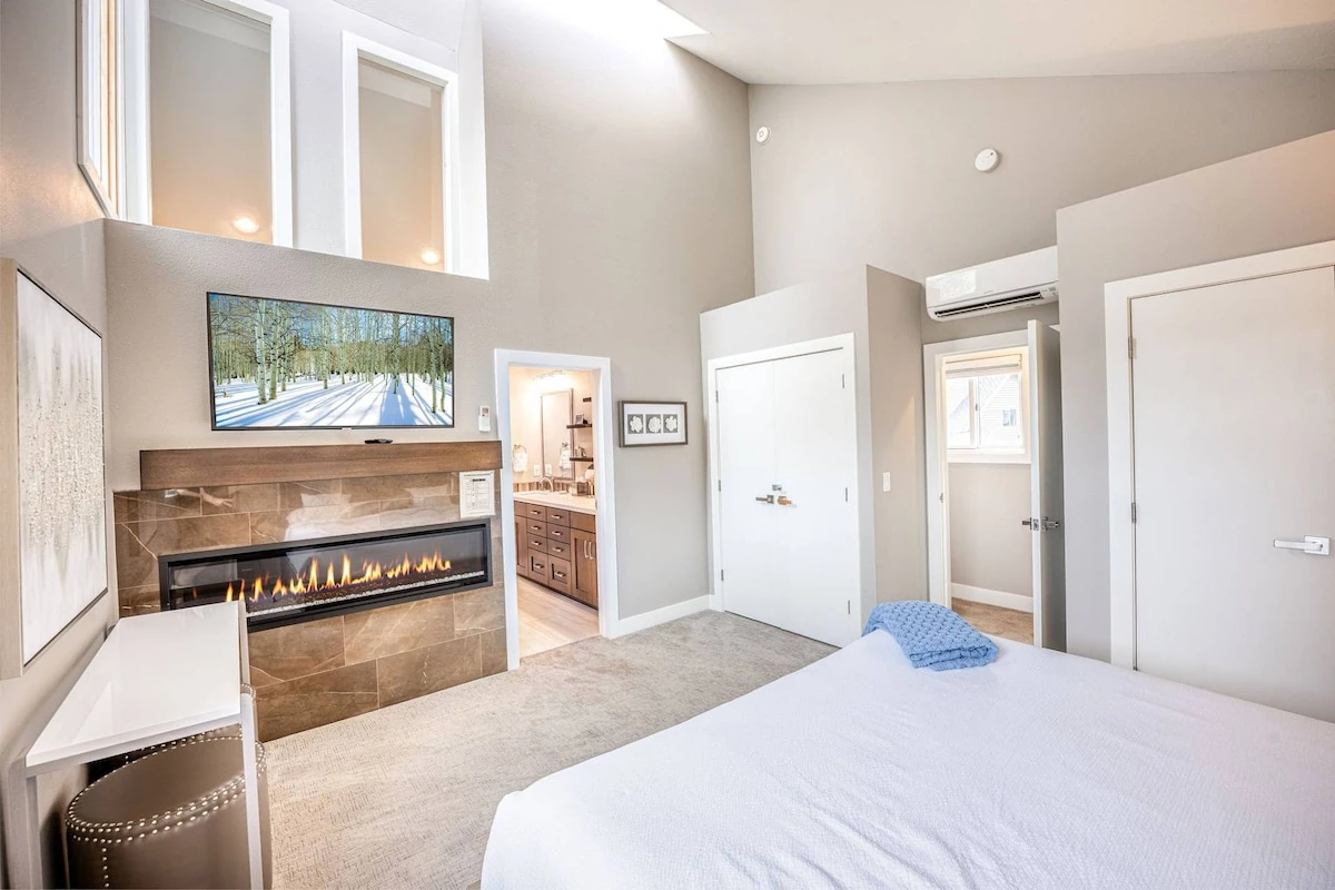 Luxurious Primary Suite with California King Bed, Fireplace, Smart TV, En Suite Bathroom, and Vaulted Ceilings