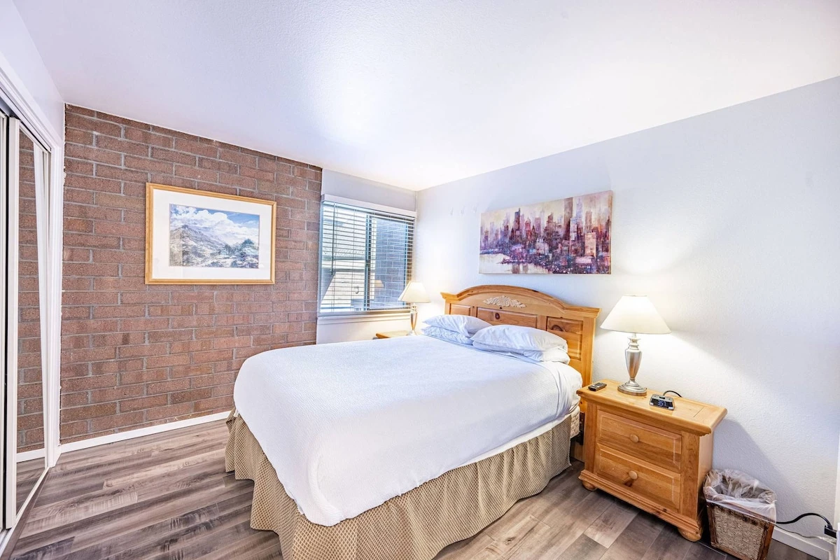 The first guest suite has an exposed brick wall and hardwood flooring - it has a warm and inviting feel. It features a Queen bed and two hardwood nigh