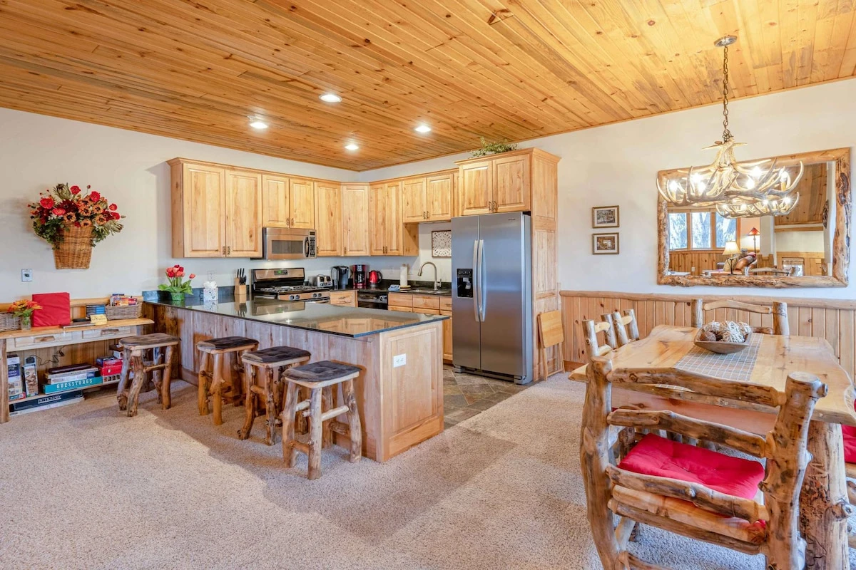 The formal dining room is decorated with an antler chandelier, custom log furniture and hardwood dining room table with plenty of comfortable seating.