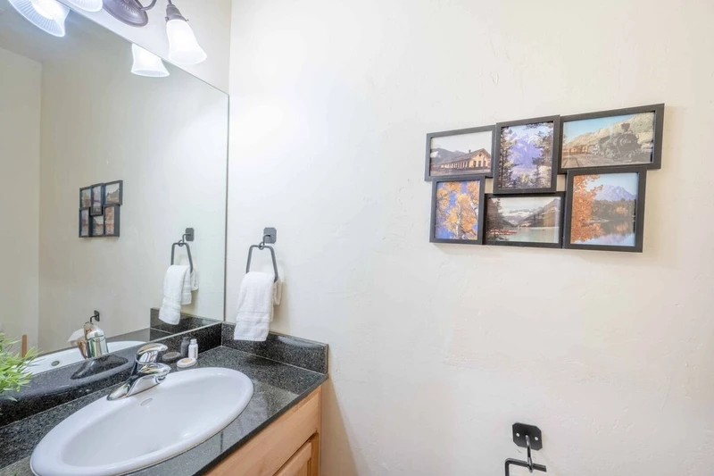 The powder room is situated next to the stairs and is designed to match the other décor of the home with a dark granite counter, vanity and toilet.