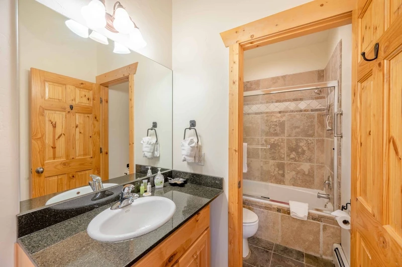 The primary suite bathroom features dark granite counters, stainless steel fixtures, Kohler sink and a fully enclosed soaker tub and shower.