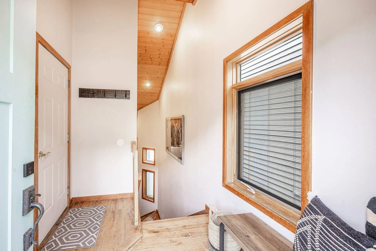 This entryway offers convenient hooks for hanging coats and bags, along with a comfortable bench for shoe removal. Perfect for a cozy and organized st