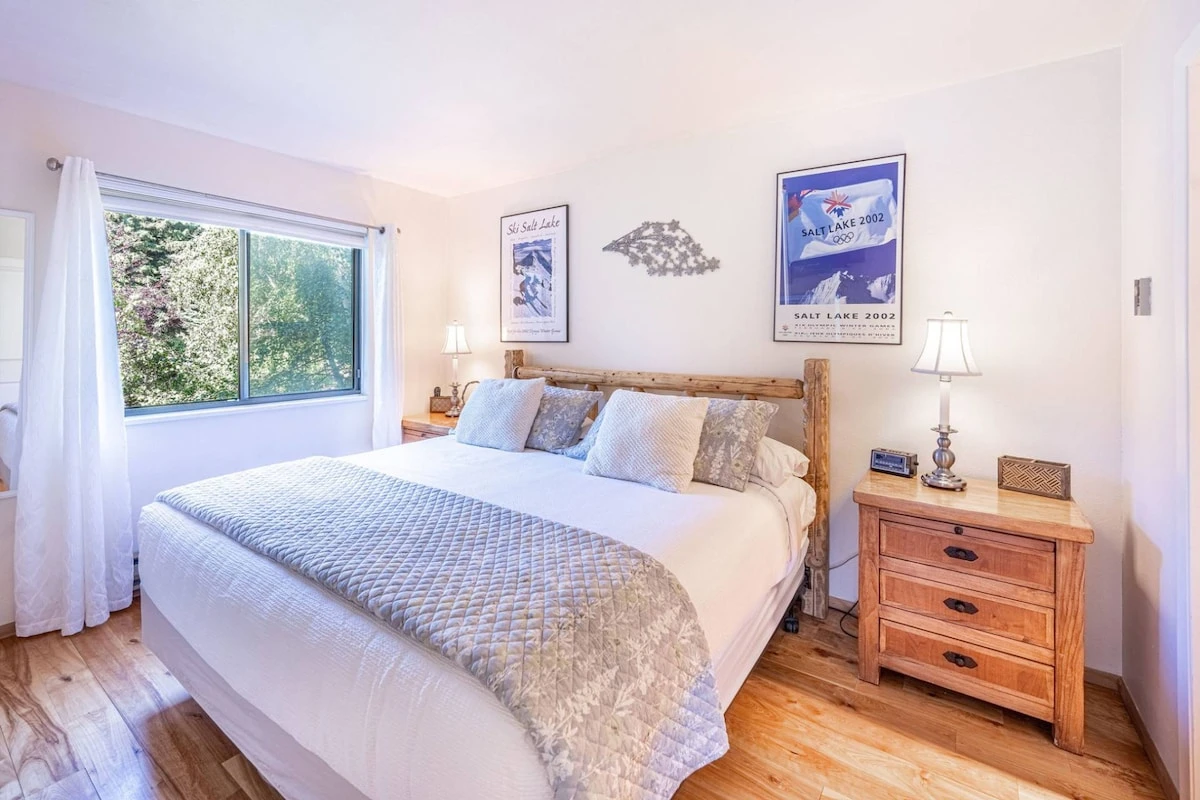 The first floor bright and spacious primary bedroom is filled with natural light, mountain views, hardwood flooring, custom log pole bed with a plush