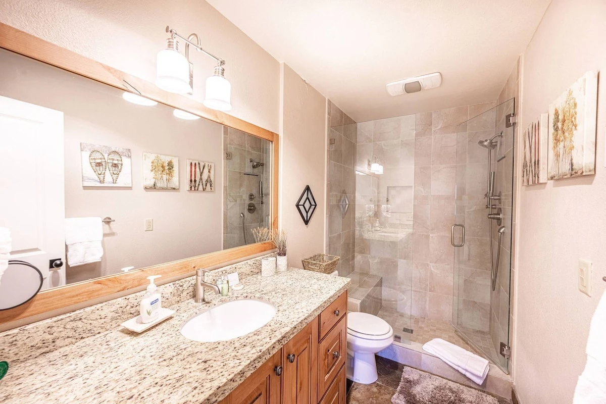 The first floor primary suite bathroom has been beautifully updated with granite countertops, luxurious walk in glass shower with dual shower head