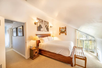 The primary suite is located at the end of the hall & has a queen size bed with hardwood bed frame & two hand carved nightstands with lamps.