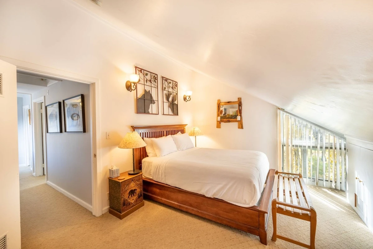 The primary suite is located at the end of the hall & has a queen size bed with hardwood bed frame & two hand carved nightstands with lamps.