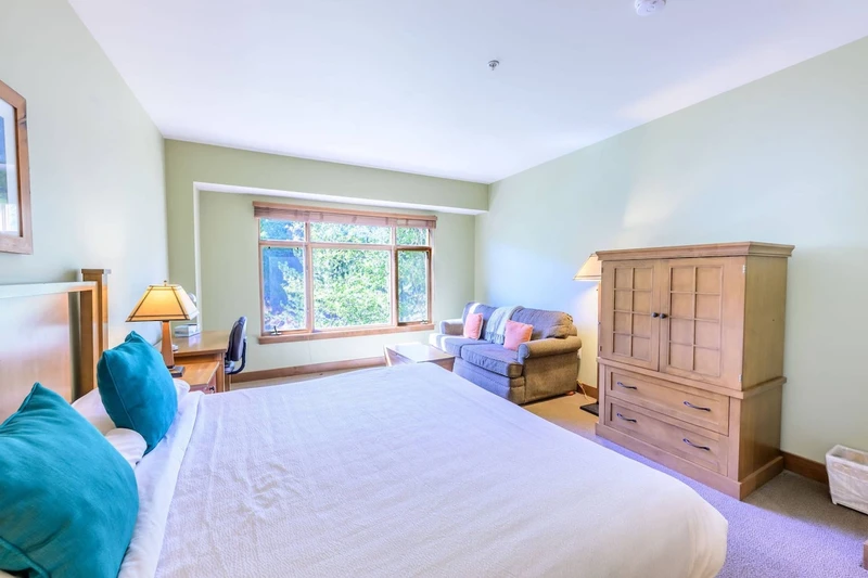 The spacious primary suite features a comfortable King-size bed with triple-sheeted linens, sofa, desk and stunning mountain views.