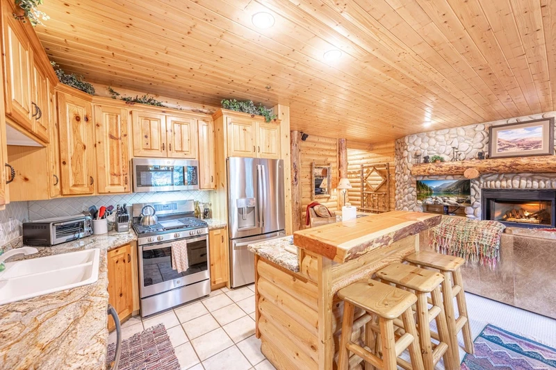 Spacious kitchen with stainless steel appliances, knotty alder cupboards, breakfast bar with seating for 3