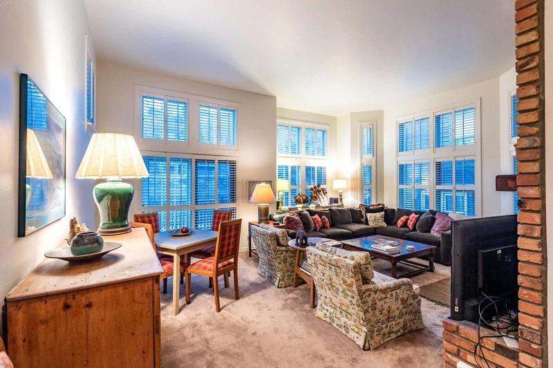 The family room features a comfortable and push L-shaped couch that surrounds a floor to ceiling brick fireplace and HDTV.
