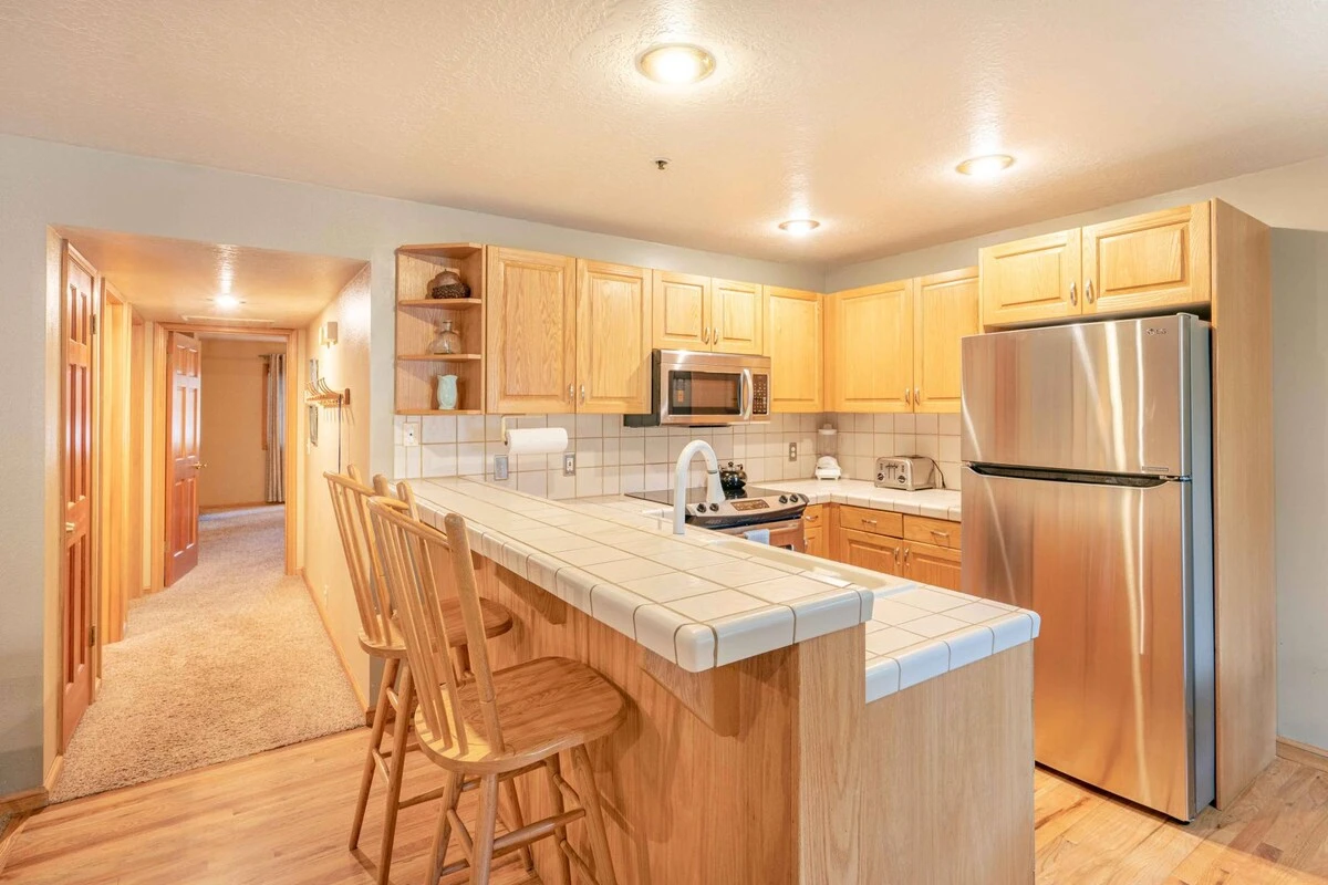 The fully stocked kitchen features hardwood flooring, breakfast bar, full size stainless steel appliances